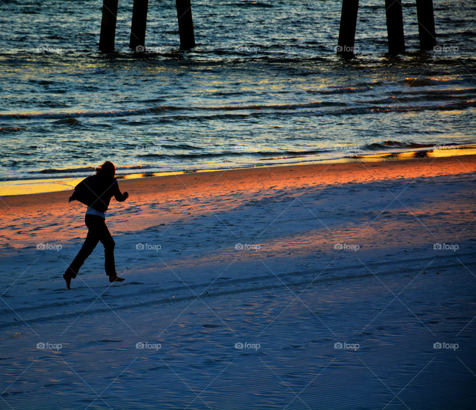 Woman running barefoot on the sandy beach!
The silhouette of the woman is a result of a brilliant sunset!