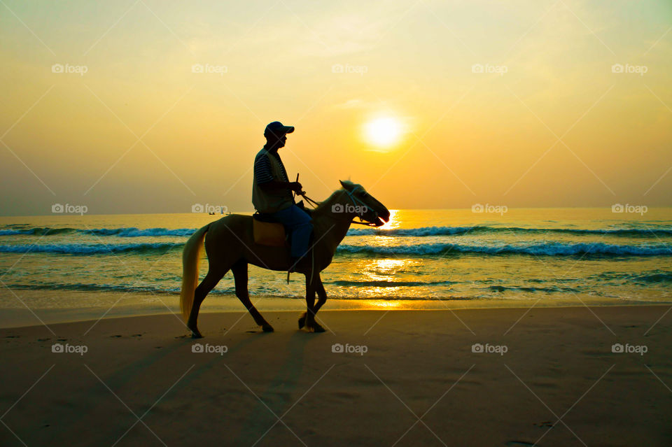 silhouette of people riding in sunset time on the beach.