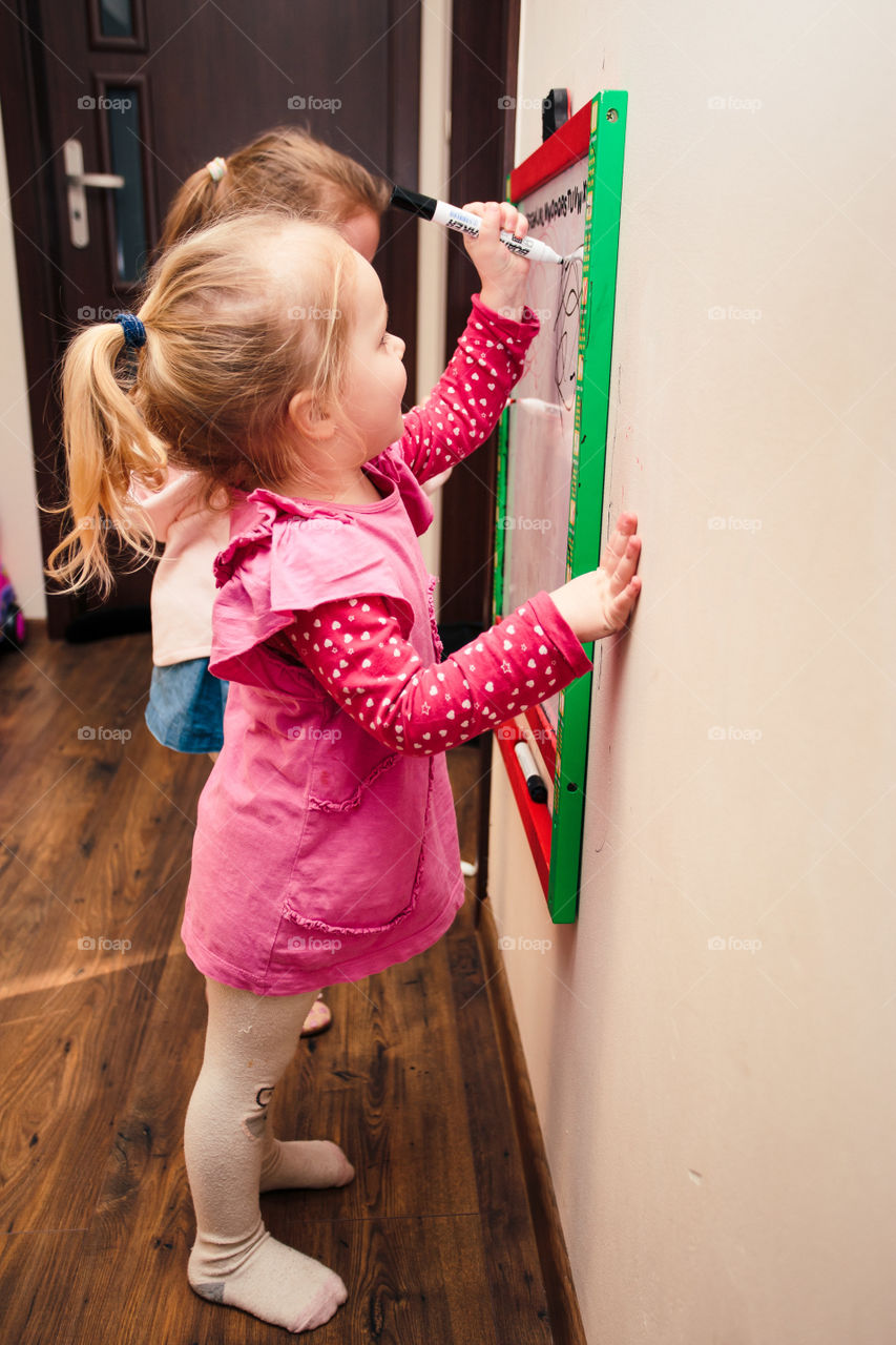 Children drawing a pictures learning a letters playing together using whiteboard and markers