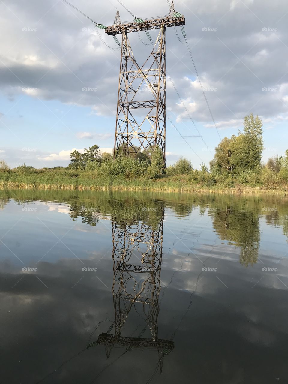 Reflection of an electric tower on the water 