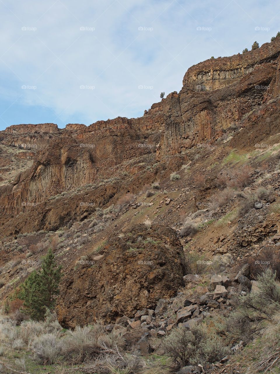 Detailed rock cliffs on a steep hill with nice blue skies in Central Oregon. 