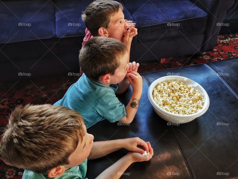 Brothers eating popcorn watching a movie