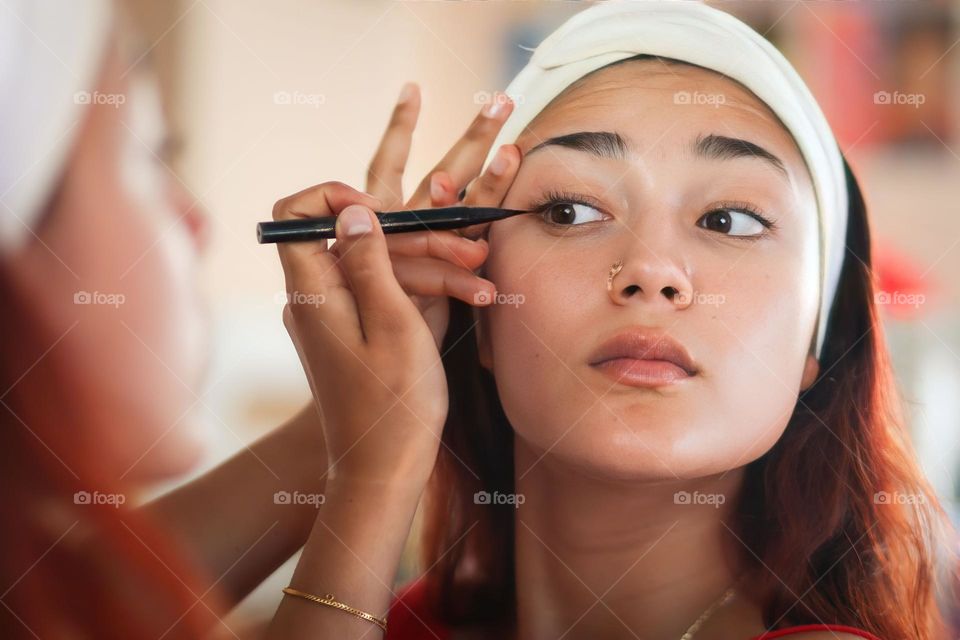 Pretty girl is putting on black eye liner