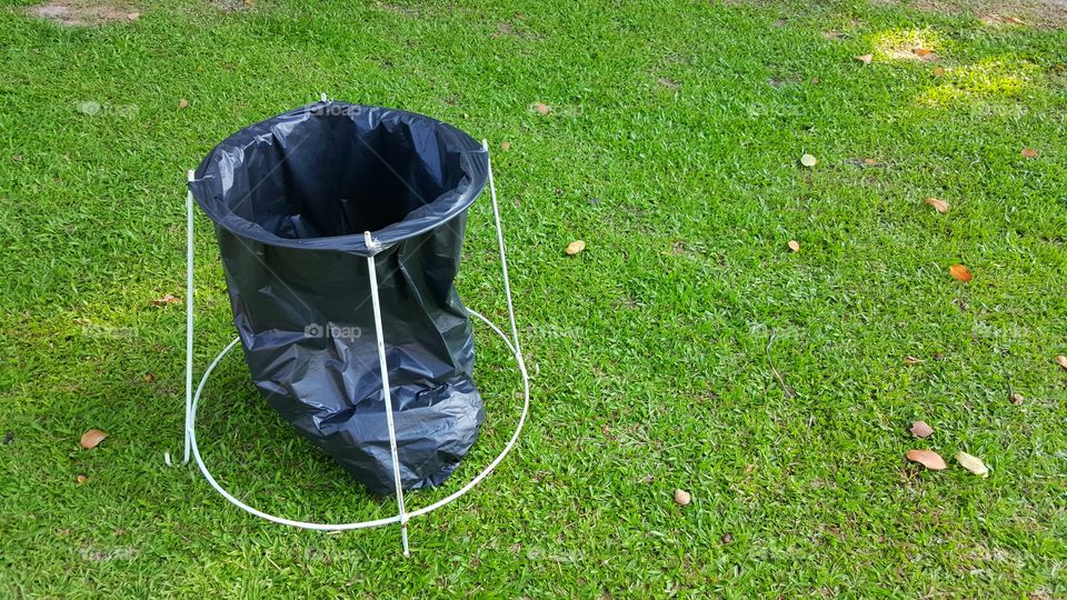 simple teporary recycle bin. teporary recycle bin made of black plastic bag and simple steel bar structure on green grass background