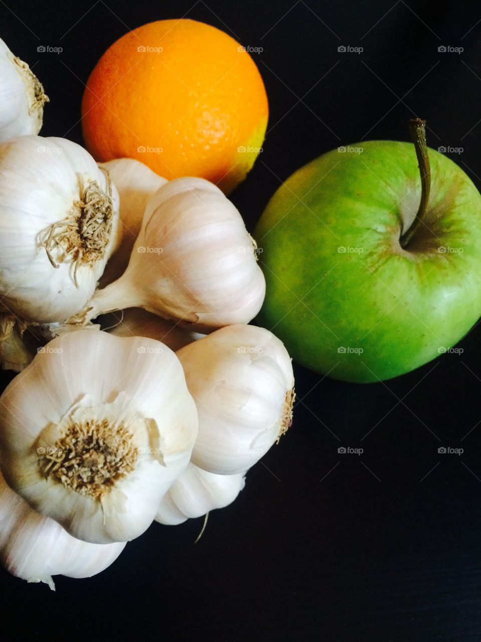 Fruits and garlic on black background