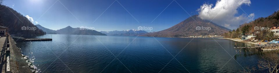 Panoramic lake with mountains and blue sky