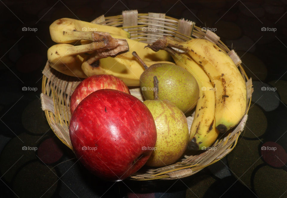in basket  apple ,pear and banana with black background.