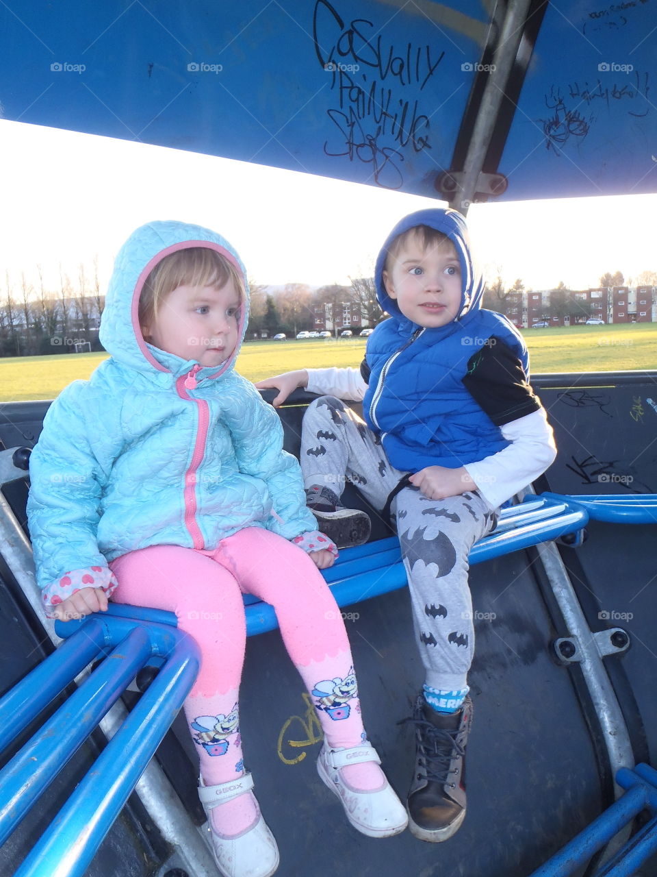 Brother and sister sitting in park