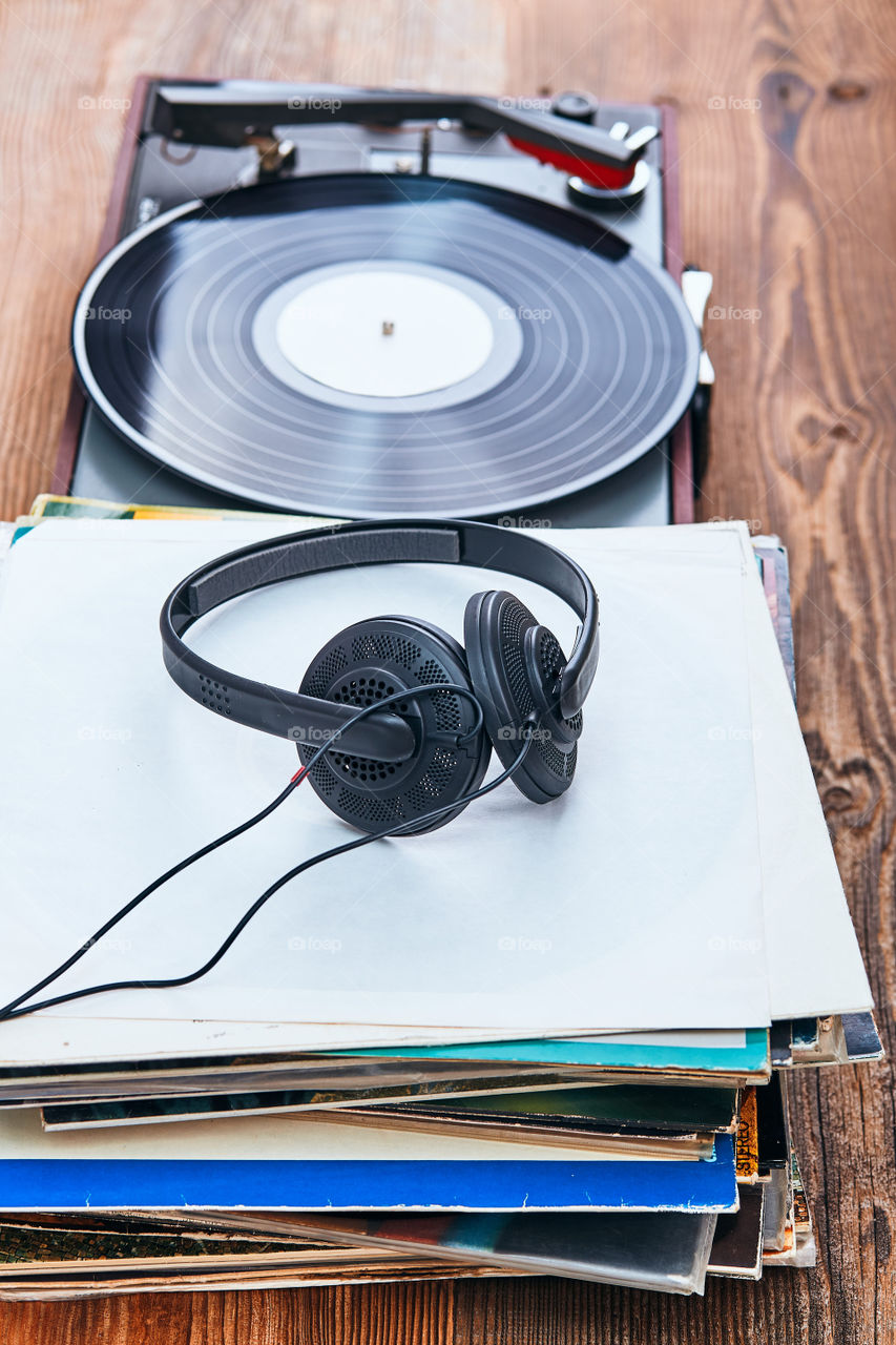 Stack of many black vinyl records, turntable vinyl player and headphones put on the stack. Classic stereo set. Candid people, real moments, authentic situations