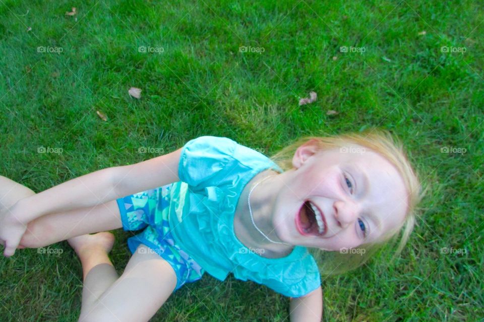 Young girl laying on the grass laughing 