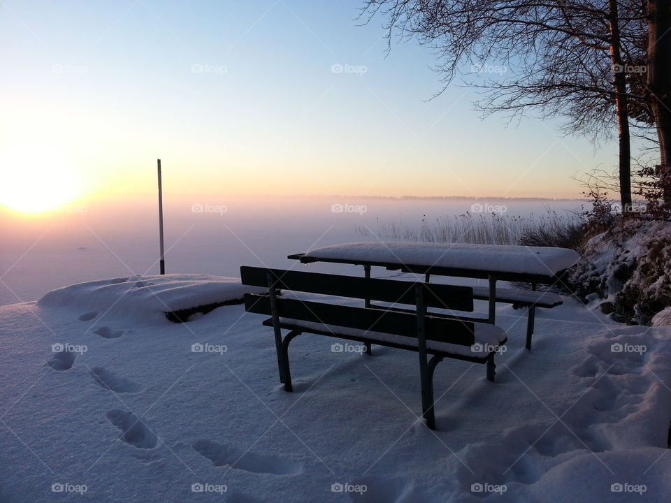 Snow covered bench at sunset