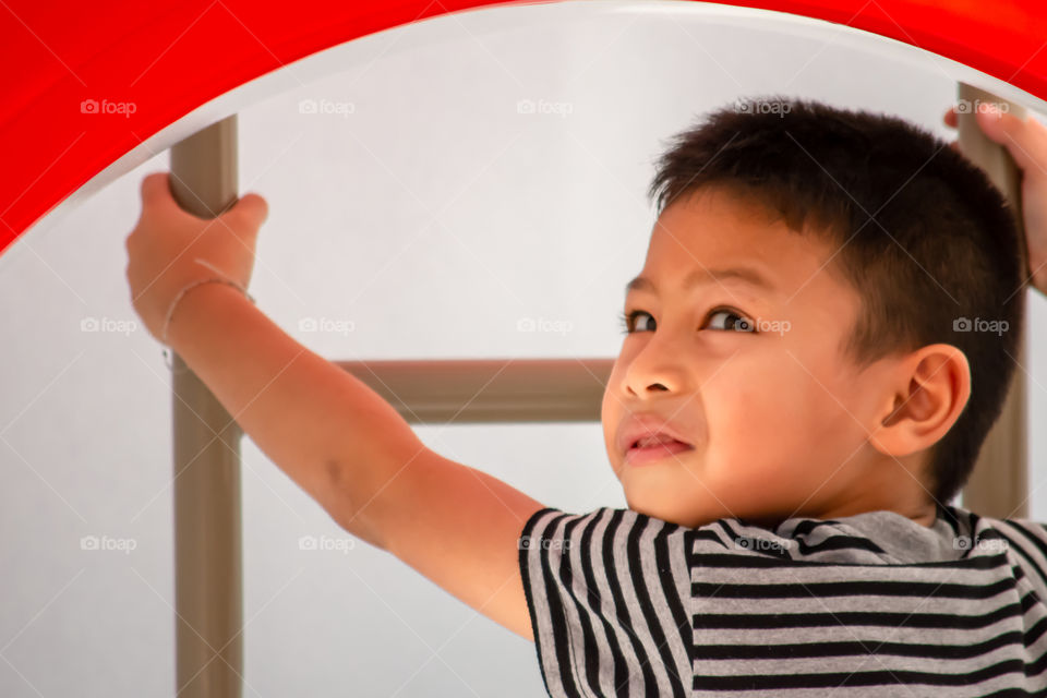 Portrait of Asian boys are climbing the ladder in the playground.