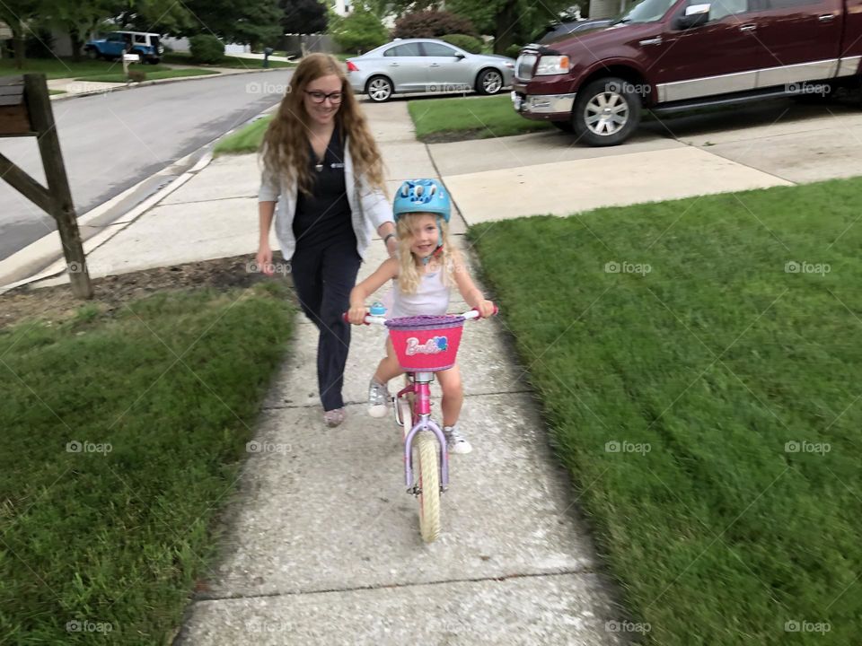 A mother teaching her daughter to ride a bicycle 