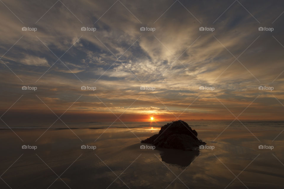 Reflection of rock in the sea during sunset