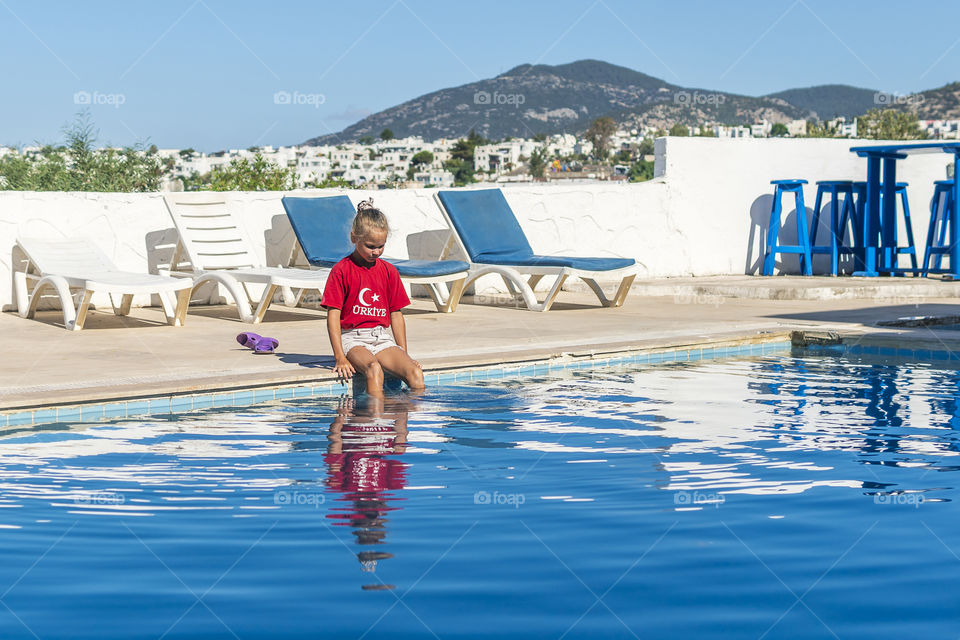 Little girl with her reflection in swimming pool