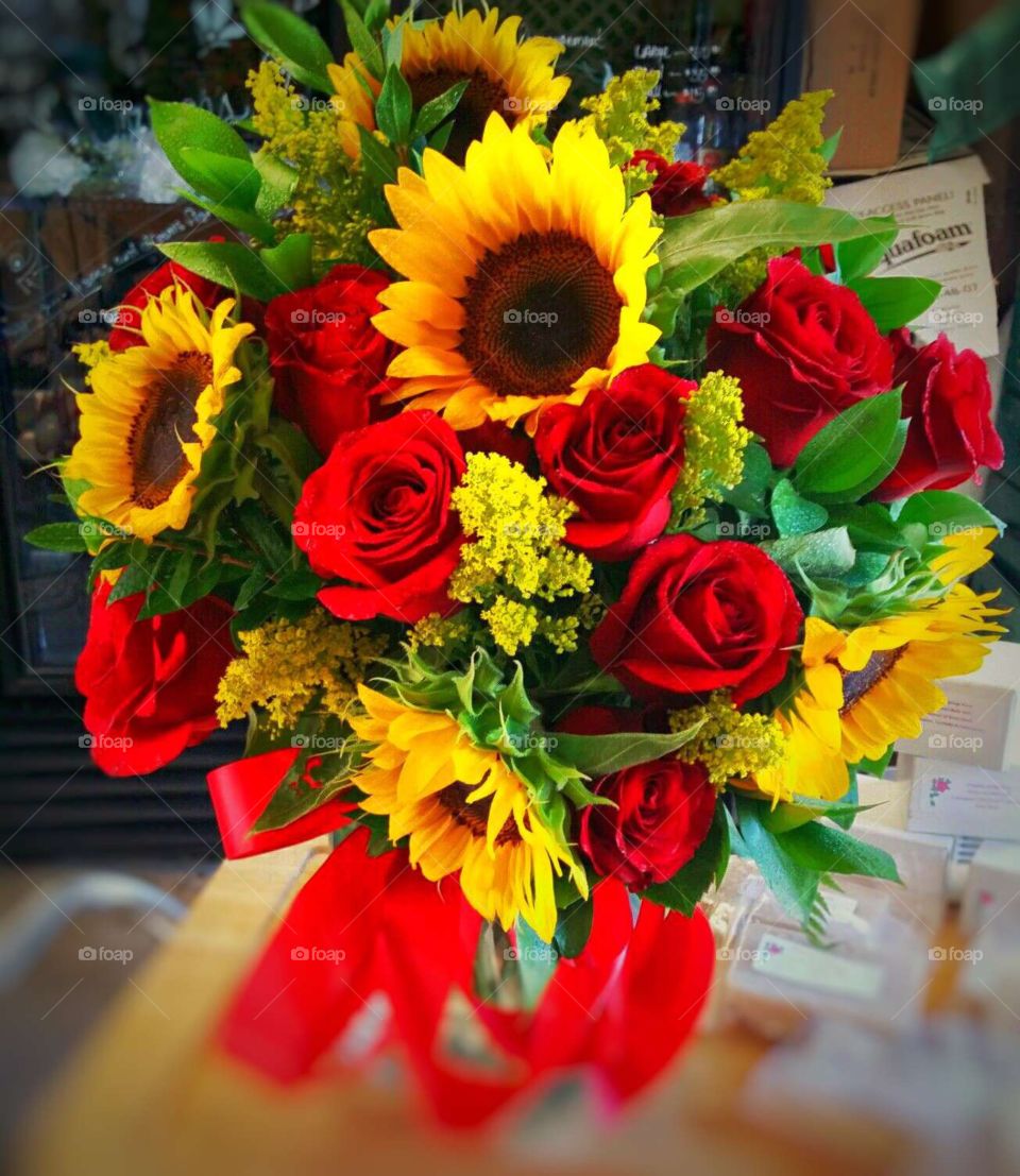 Bouquet of roses and sunflowers in a pretty vase with red ribbon