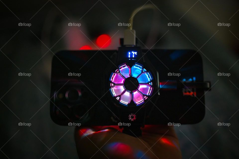 Smartphone RGB Light. Cooling fan for smartphone gaming high performance. keep the phone cool. ambient light. dark room and cinematic shoot. man holding phone.