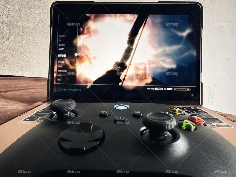 Playing Skyrim Videogame through a Xbox controller and laptop.