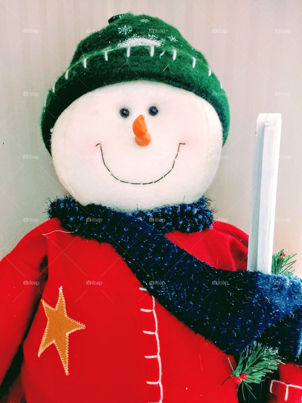 A snowman in a red jacket and green knit hat