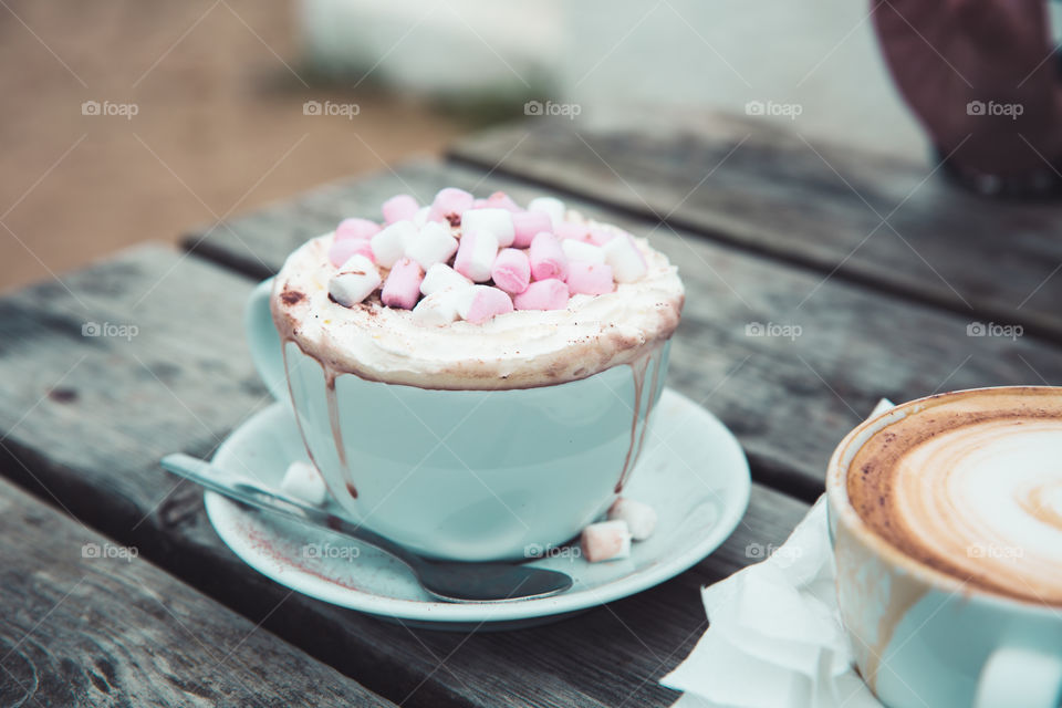 A luxury hot chocolate with whipped cream and marshmallows in a cup and saucer