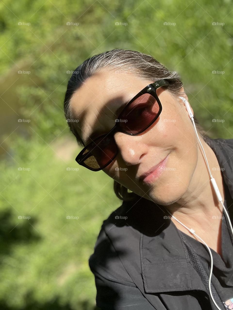 Sunny fall day smiling face portrait, sunglasses and listening to music, greenery in back 