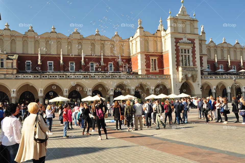 Kraków Poland main market square with many people of various age admiring soap bubbles event in sunny afternoon