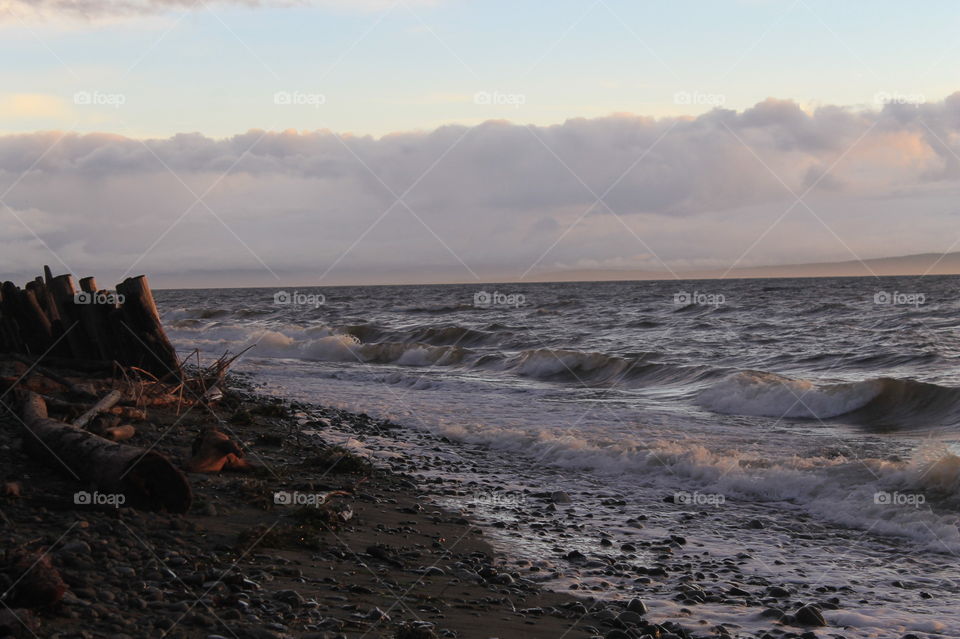 Some sunrise shots of the ocean on a windy Pacific Northwest morning. The high tide created frothy waves breaking on the shore. There were some clouds but the sun shone through creating beautiful colour in the sky and sea.