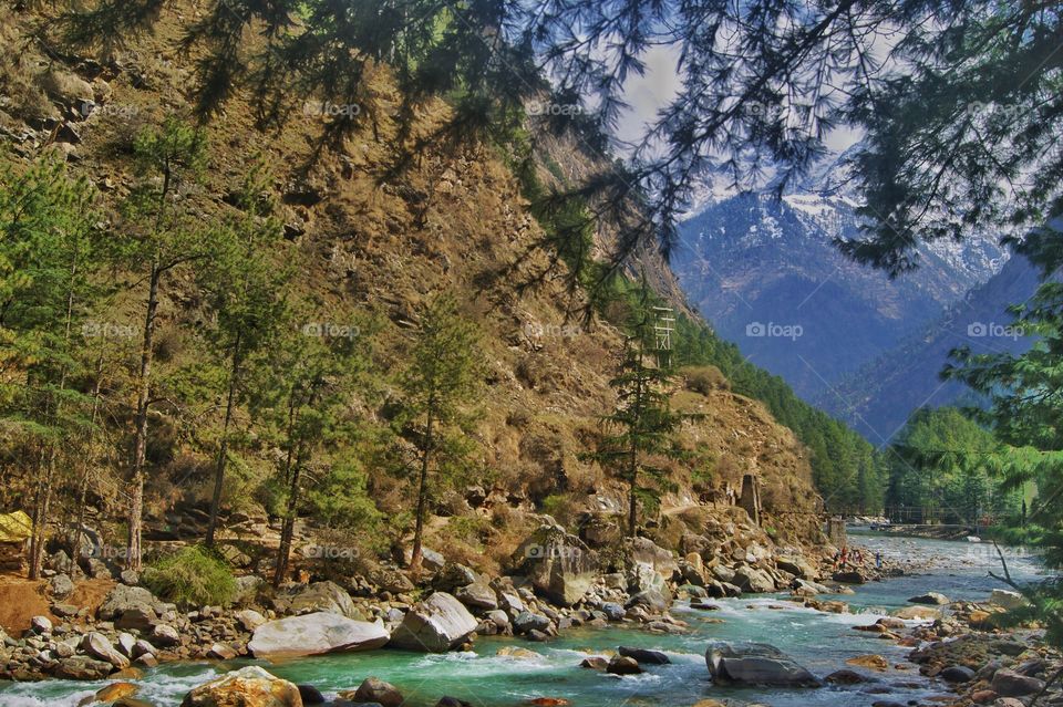 A snow covered mountain from where a crystal clear Parvati river is flowing with many rocks in it. This was a view from one of my cottage in Himachal India.