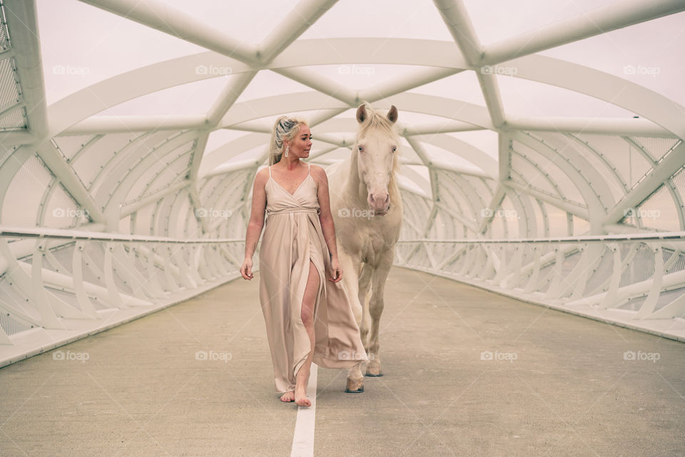 Woman walking with her horse on a bridge