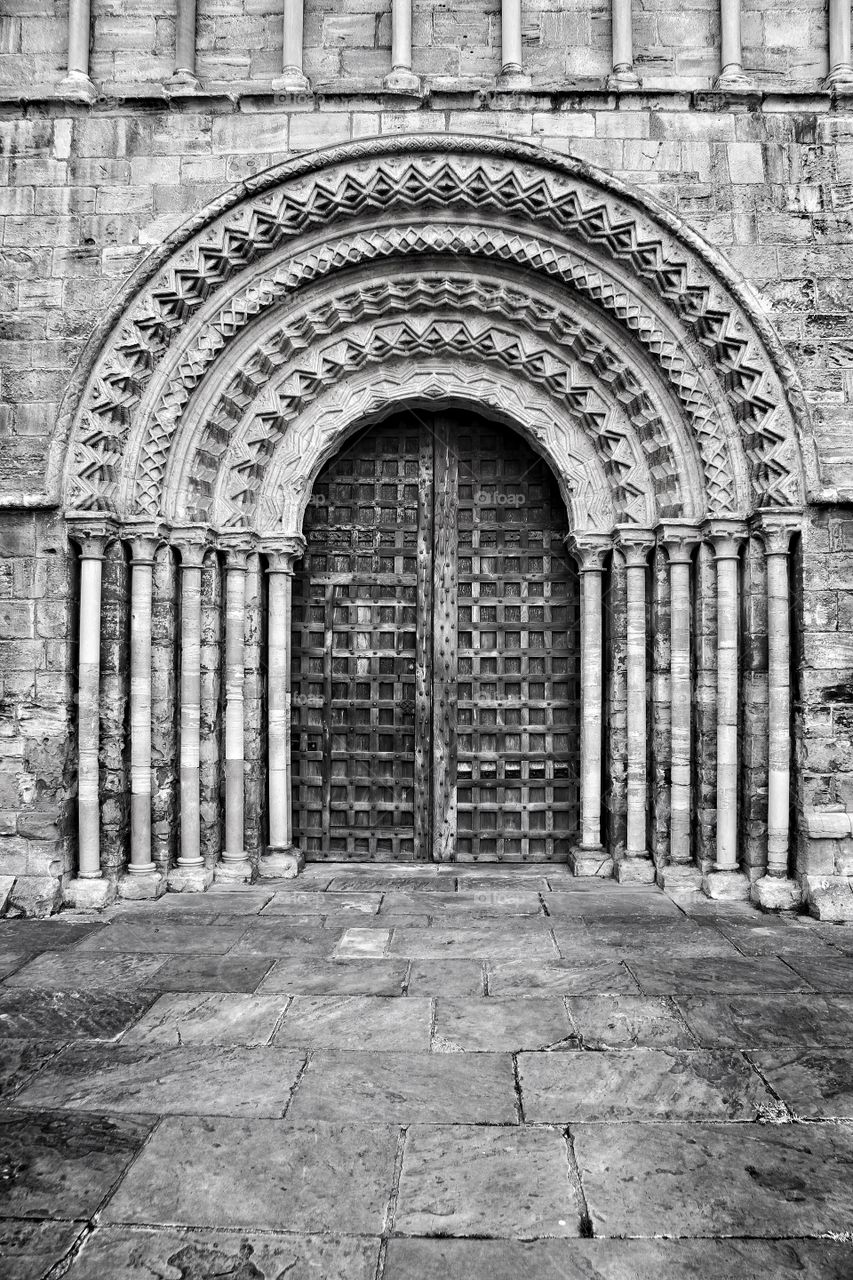Cathedral Doorway. A monochrome image of an ornate church door with stone carvings and pillars surrounding it.
