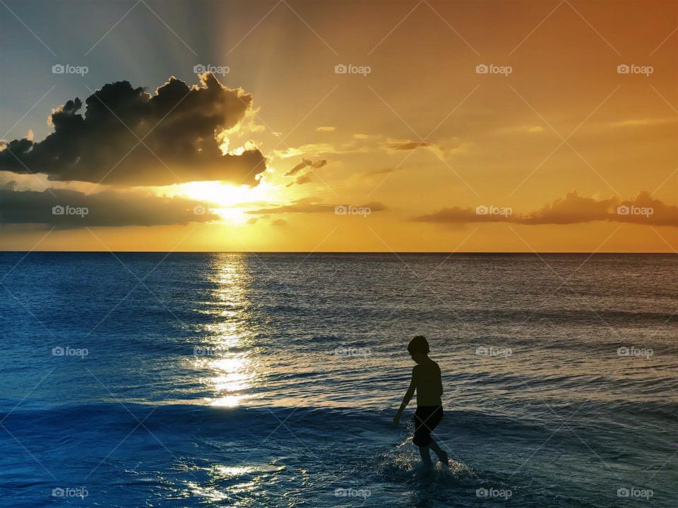 Boy in the surf at sunset.