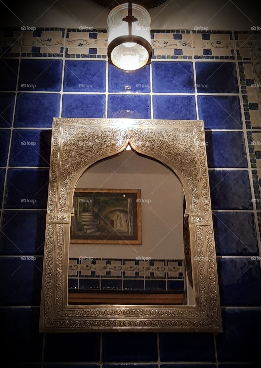 wall lamp illuminating a bathroom mirror framed in metal