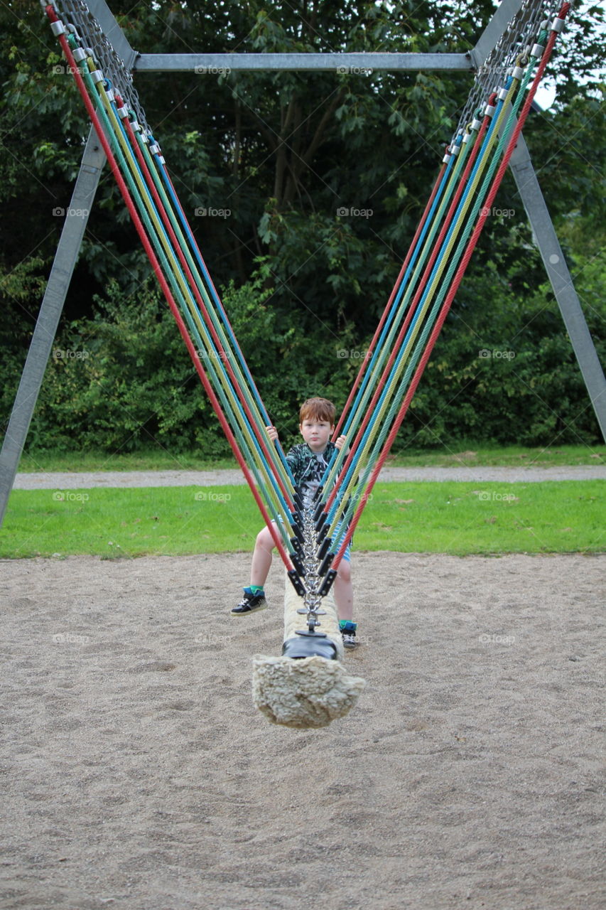 Boy sitting on swing in the playground