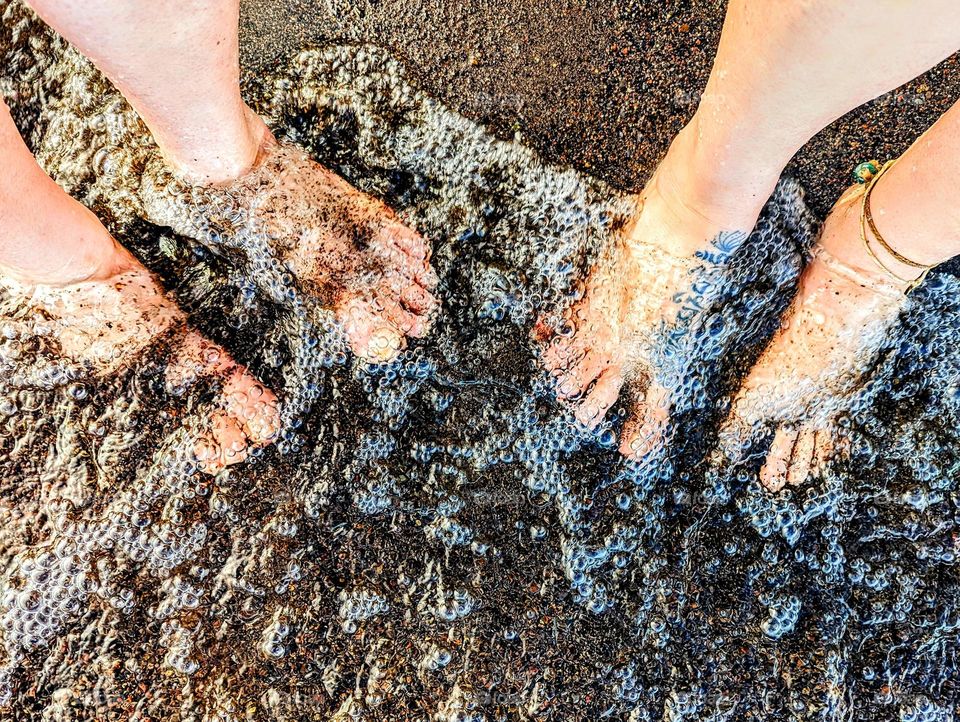 Sandy feet covered in bubbles on a beach. Summer adventures with friends and family.
