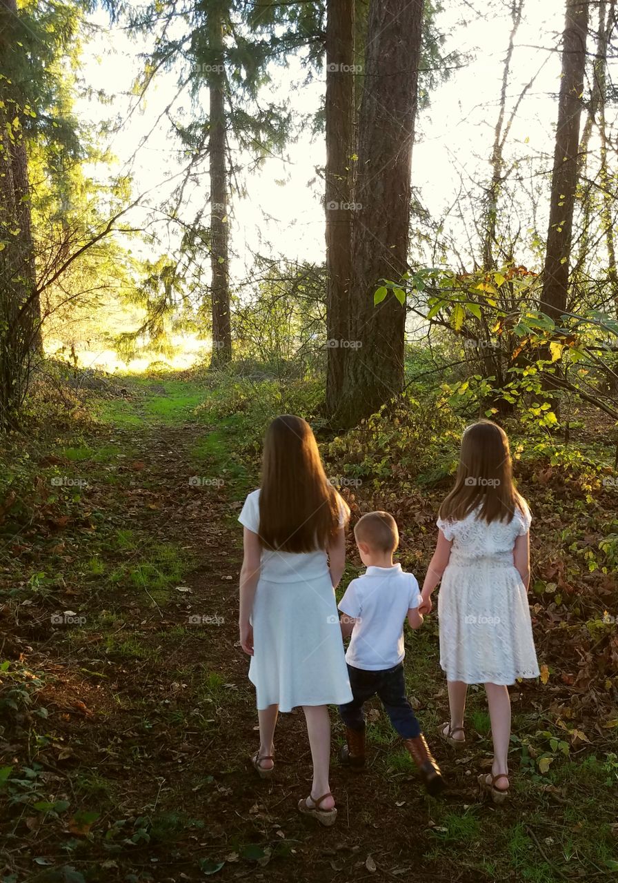 Three siblings walking through the forest