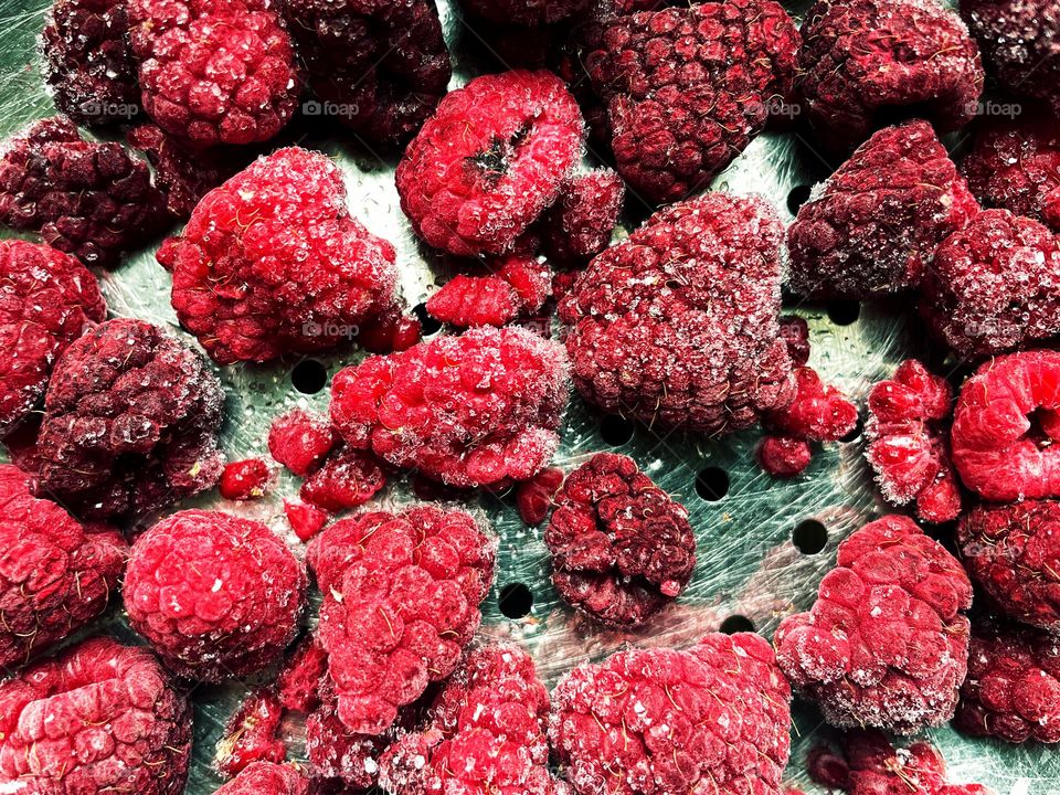 Close-up of frozen raspberries in a metal sieve 