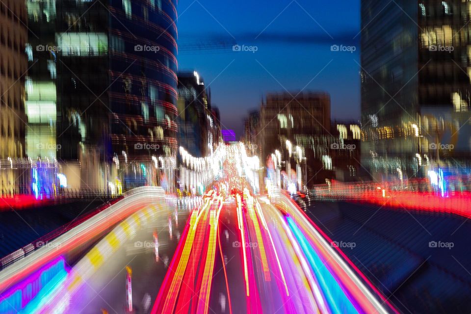 Beautiful blurry night view with colorful lights of the city of Brussels from the bridge to the road with passing cars in the style of freezelight, close-up side view.