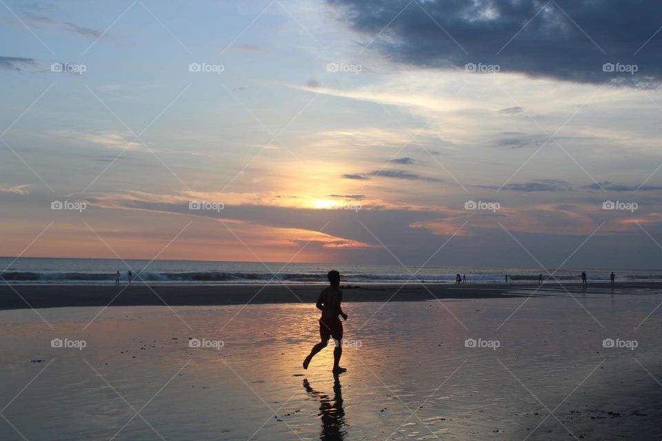Evening walks and running hours along picturesque Seminyak coastline of Bali island. 