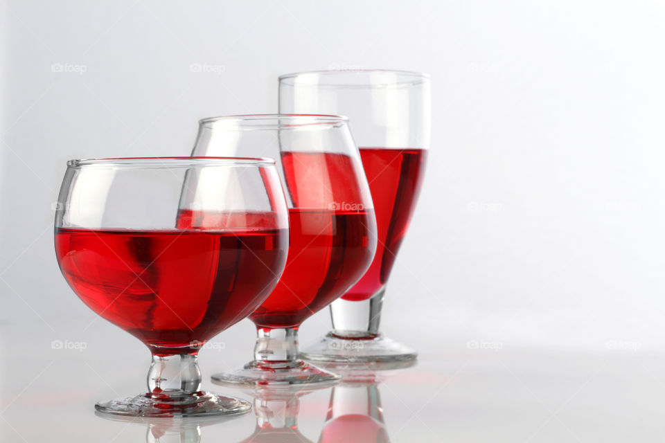 Red wine glasses on white reflective background