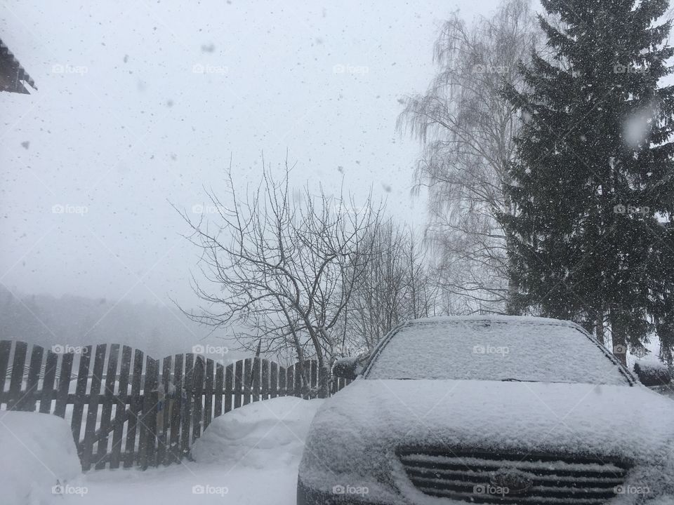 Снегопад зимой на фоне машины KIA