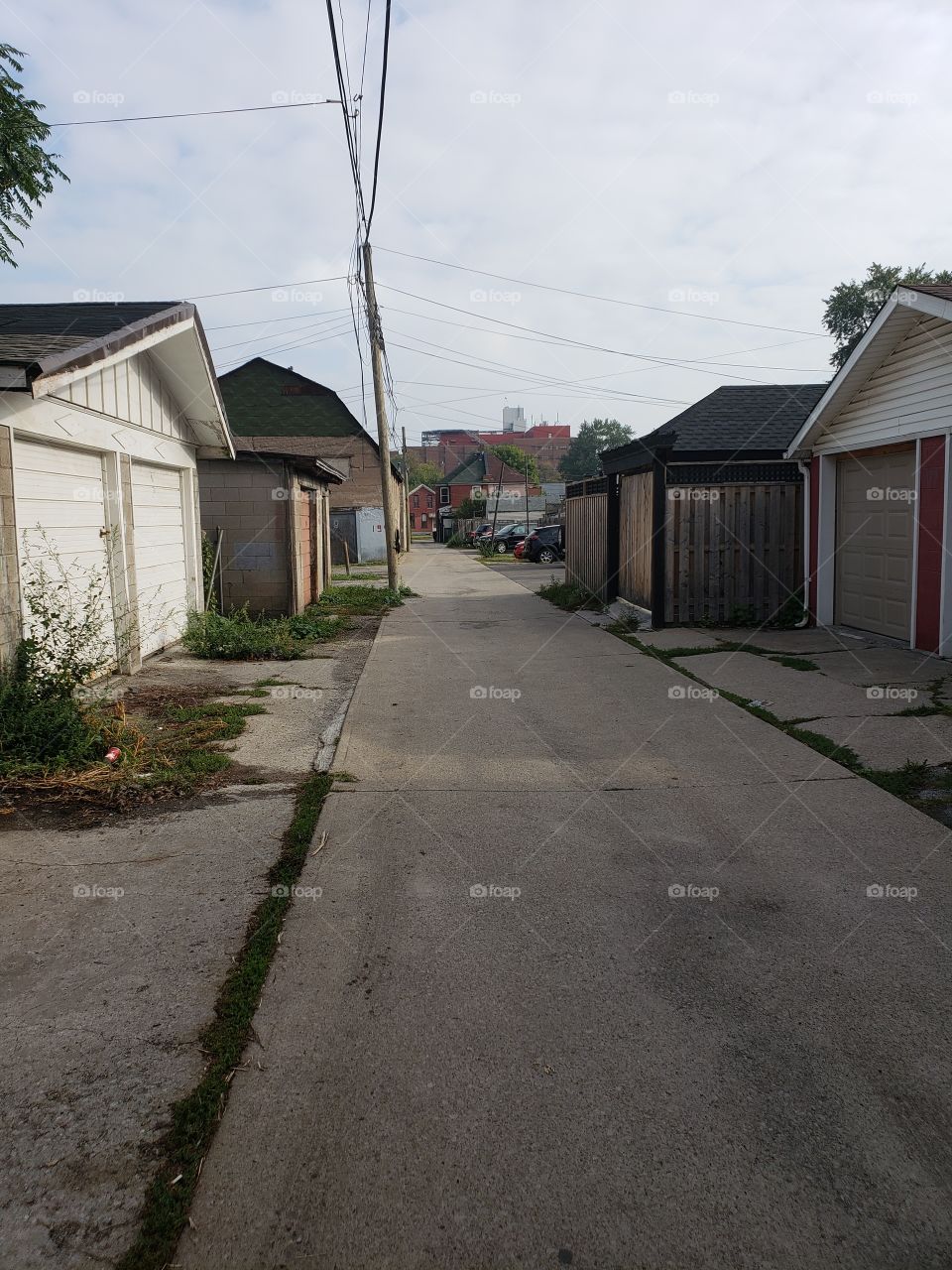 Alleyway in an old run-down neighborhood with garages and electrical wires