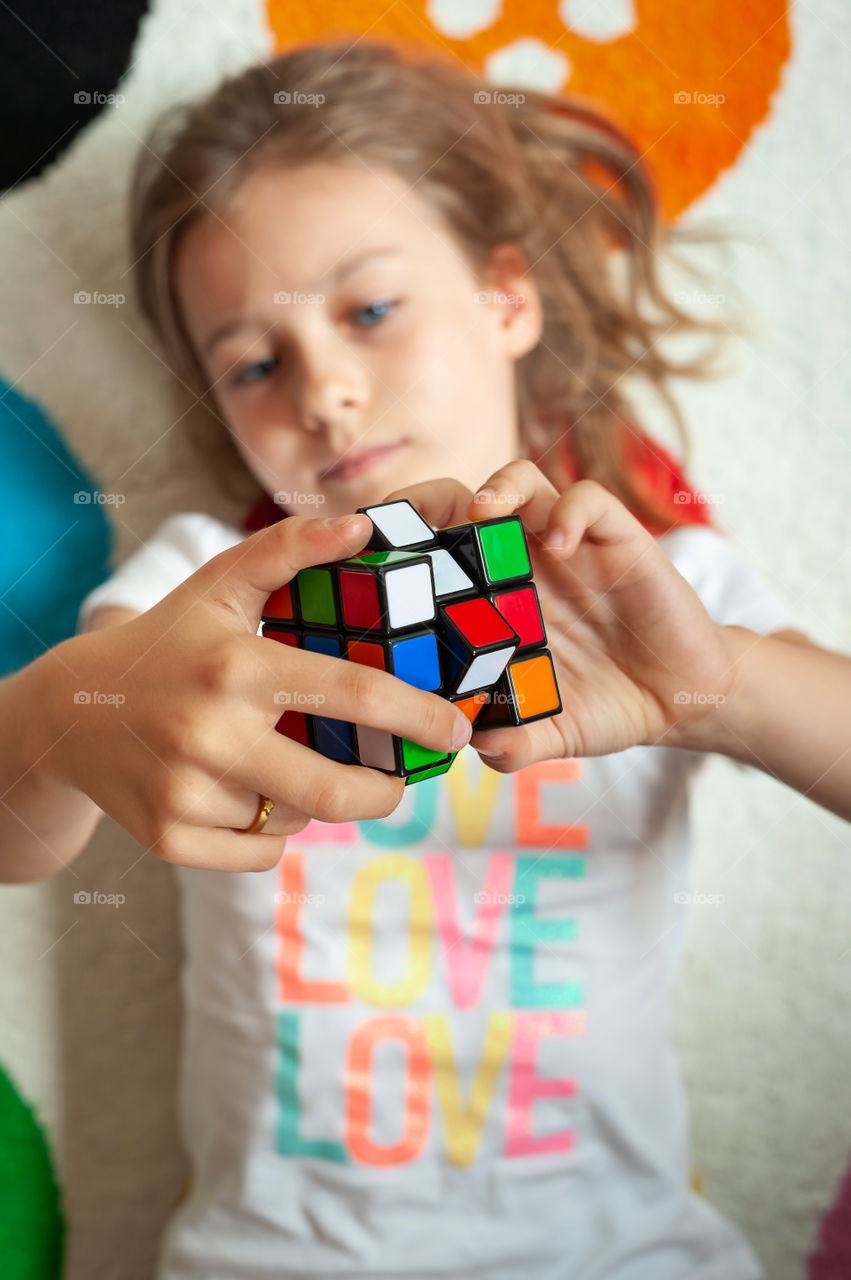 Young girl play with Rubik's cube.