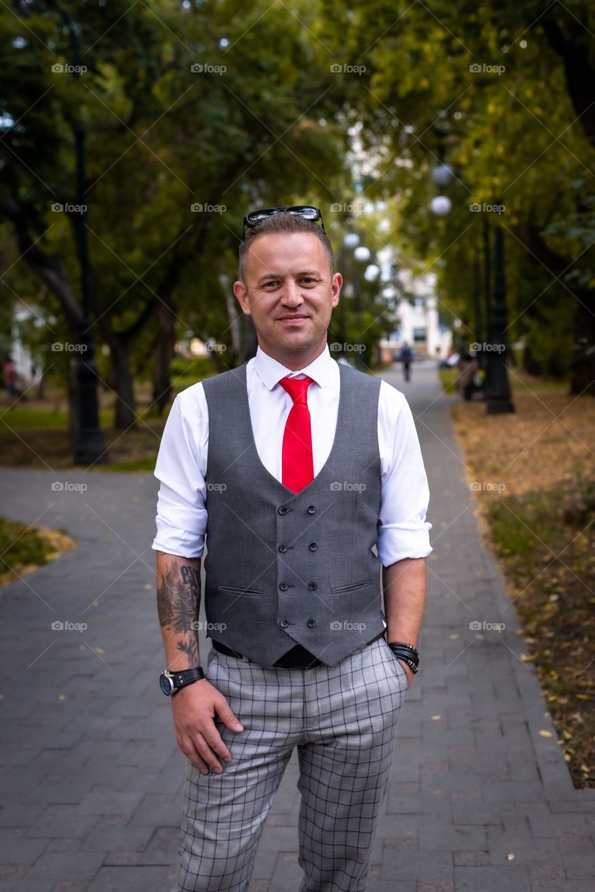 young man with tattoos walks in the summer in the park