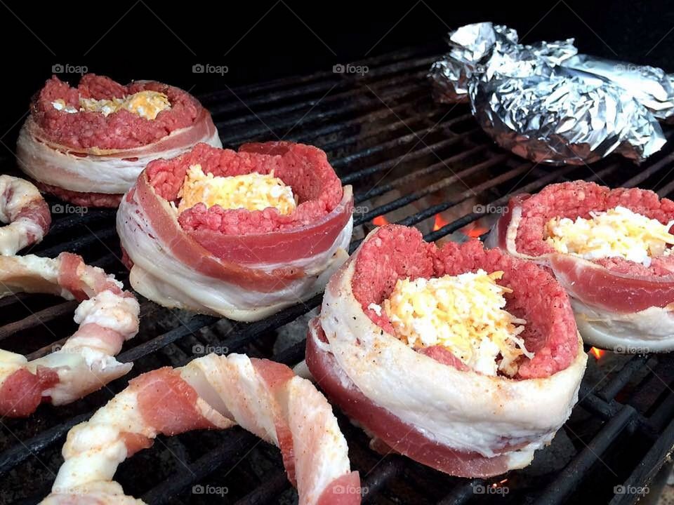 Grilled bacon wrapped hamburgers with cream cheese, & shredded cheese with bacon wrapped onion rings 