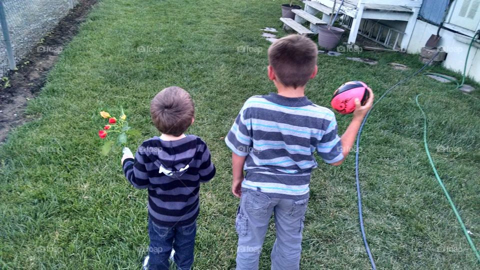 kids. playing in yard plating ball and picking flowers