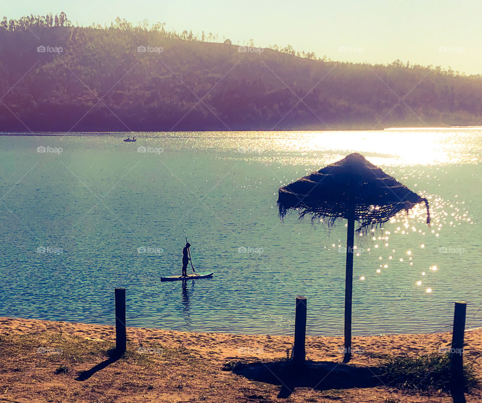 Paddle boarder on the river in the bright morning summer sun