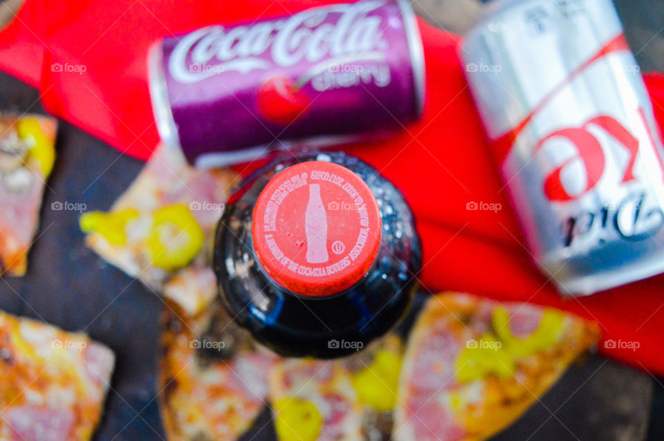 Coca-Cola and cherry Coke and Diet Coke with pizza on a rustic red background