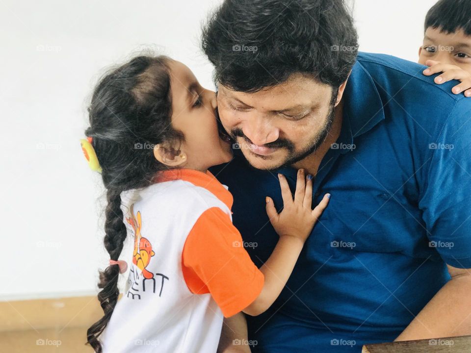 Daughter fun with father by biting father’s cheeks 