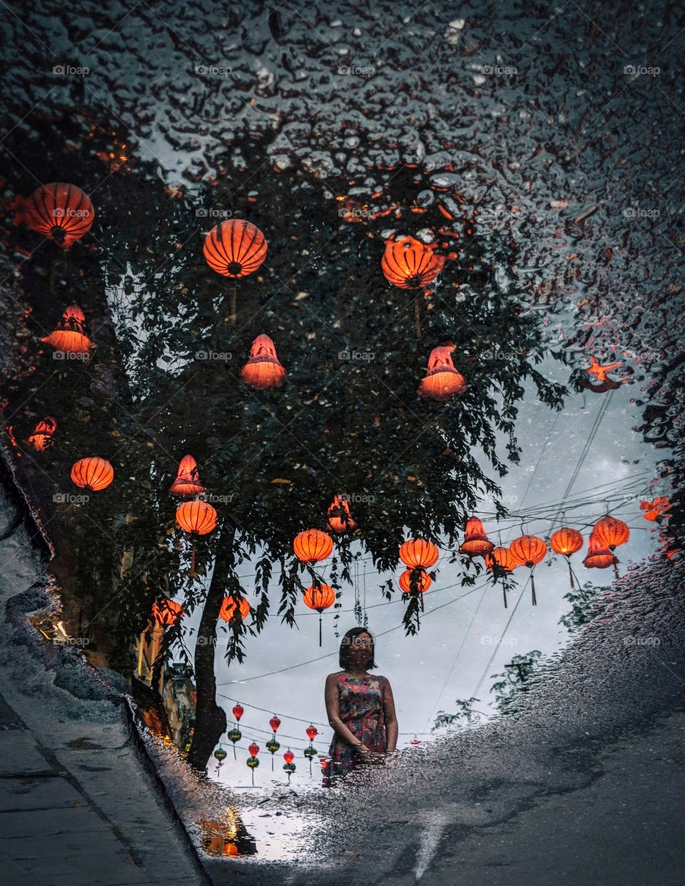 Red hanging lanterns and a girl reflected in a puddle of water