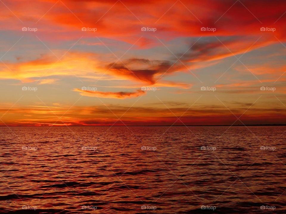 A Breathtaking descending sunset with picturesque peach colored Lenticular clouds over the Gulf of Mexico